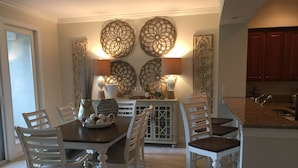 Un comedor con mesa de madera, sillas blancas y decoración mural.