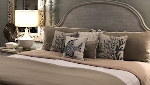 Un dormitorio con cama, almohadas, lámpara y espejo.