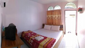Quarto com uma cama, mesa de cabeceira de madeira, janela com cortinas e uma pequena mesa com uma garrafa de água.