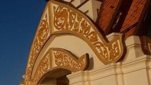 Um edifício com fachada branca e um arco decorativo com padrões elaborados.