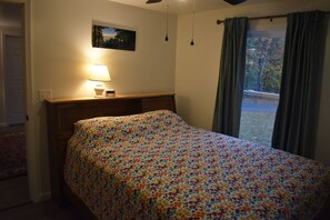 A bedroom with a bed, a bedside table with a lamp, a window with curtains, and a door. - Short walk to the lake! (Huntingdon)