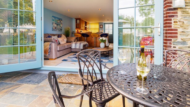 Una casa moderna con un patio che include un tavolo da pranzo, sedie e un bicchiere di vino.