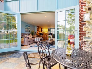 Een modern huis met een patio, compleet met eettafel, stoelen en een glas wijn.