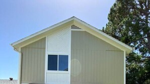 A two-story house with a front porch, a blue door, and a small front yard.