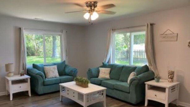 A living room with two green sofas, a white coffee table, and a ceiling fan.