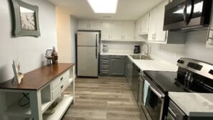A modern kitchen with white cabinets, stainless steel appliances, and a wooden countertop.