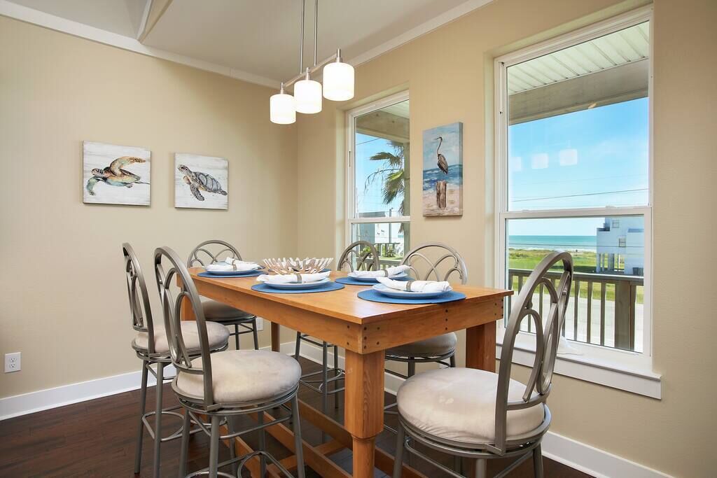 A dining area with a wooden table set for four, metal chairs, and artwork on the walls.