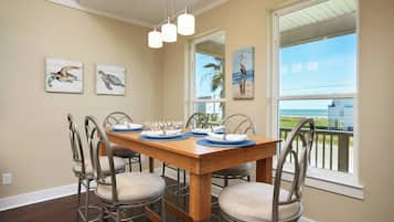A dining area with a wooden table set for four, metal chairs, and artwork on the walls.