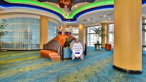 A spacious lobby with a check-in desk, patterned carpet, and large windows. - Lattitude Adjustment - Ocean Walk (Daytona Beach)