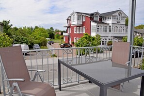 A balcony with two chairs and a table, overlooking a parking area and a building with a balcony. - 04 Ferienwohnung Greta mit Balkon - Appartementhaus Greta im Ostseebad (Sellin)