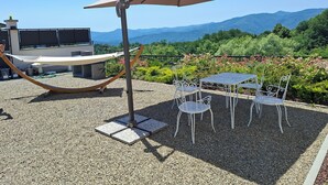 Une terrasse avec un hamac, des sièges d’extérieur et un grand parasol.