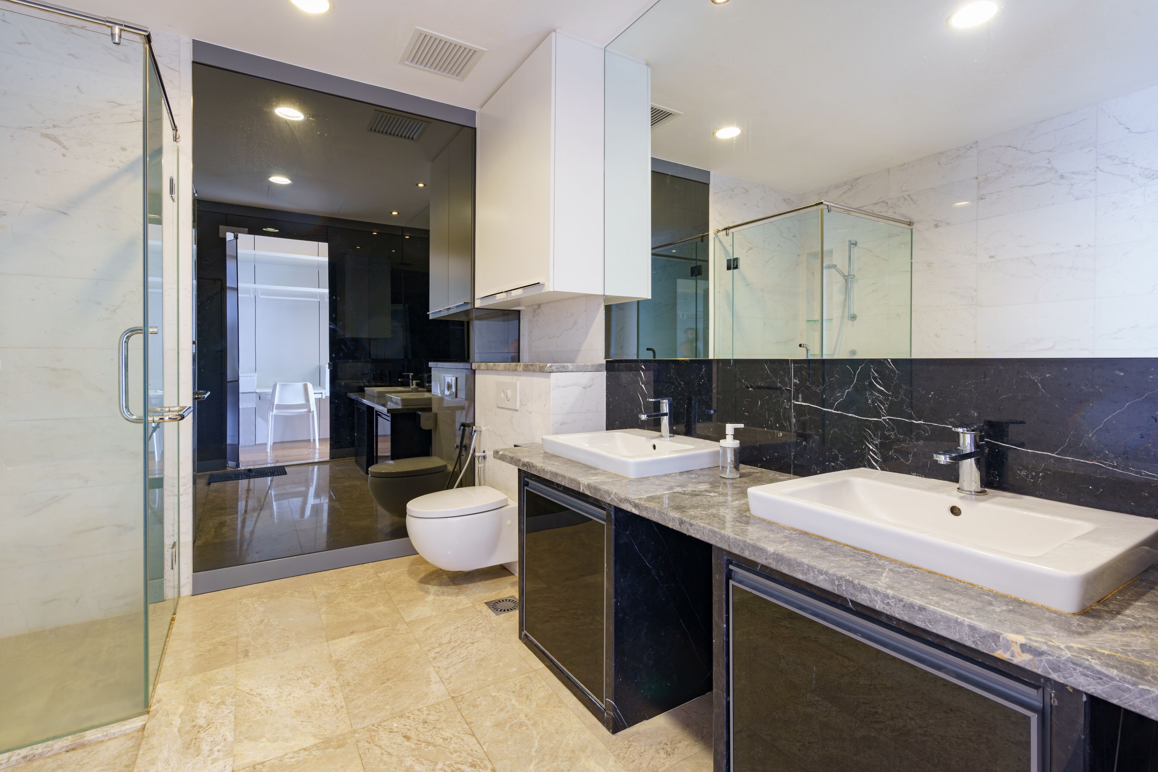 A modern bathroom with two sinks, a glass shower enclosure, and a toilet.