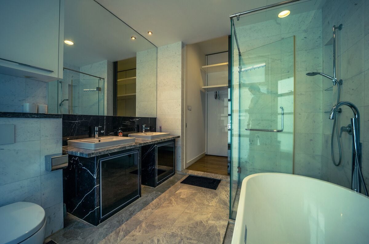 Un baño moderno con ducha de vidrio, bañera independiente y tocador doble.
