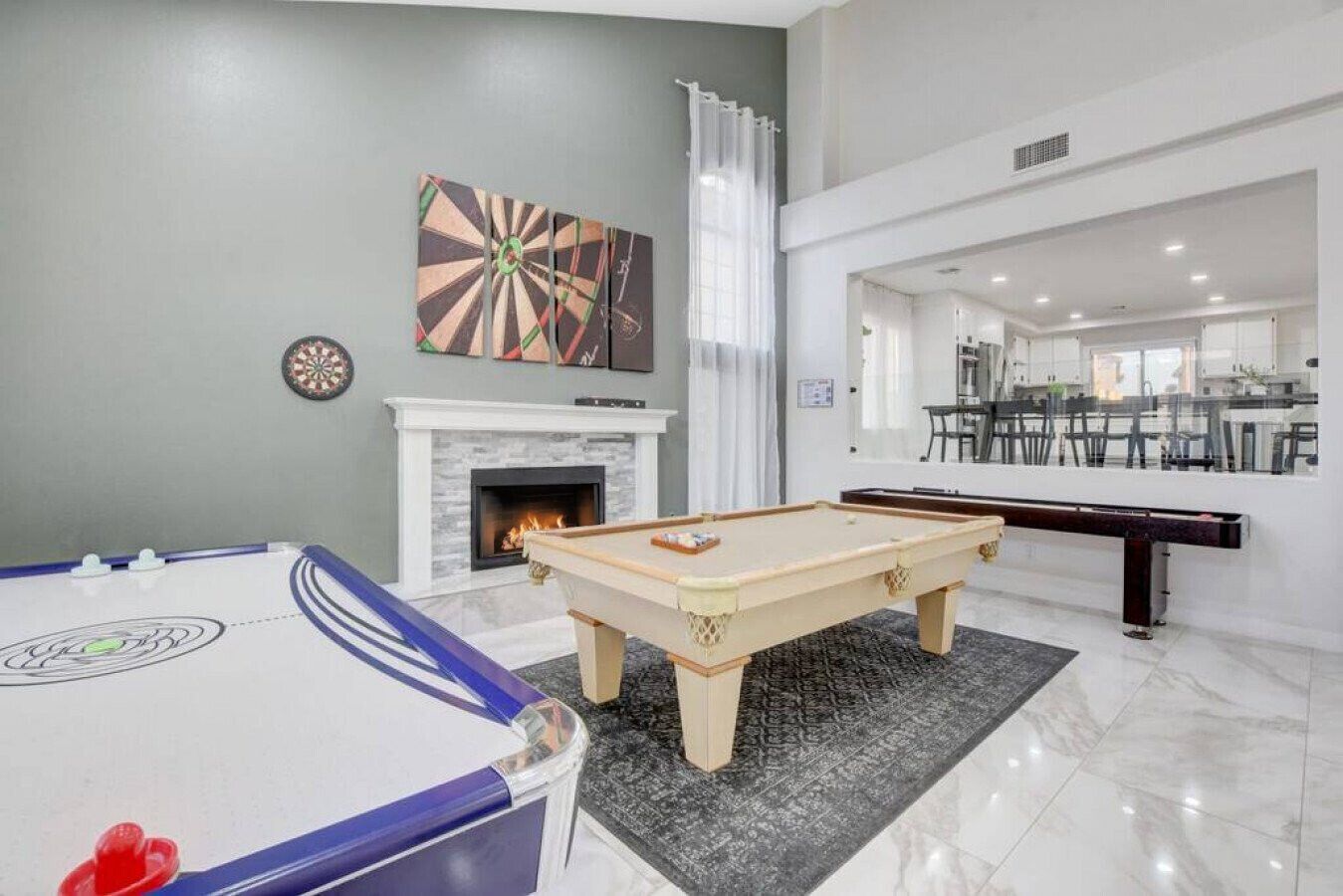 Un salon moderne équipé d’une table de billard, d’un jeu de fléchettes et d’une cheminée.