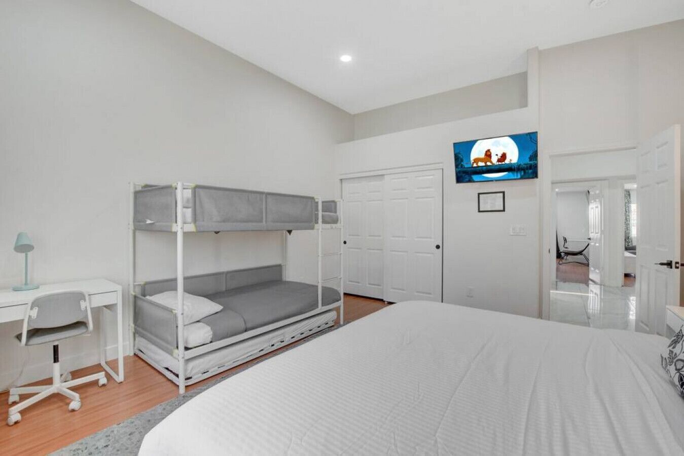 A bedroom with bunk beds, a desk with a chair, a television, and a wardrobe.
