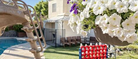 A poolside area with a metal ladder, a hanging flower arrangement, and outdoor furniture.