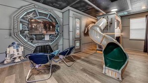 Huoneessa on suuri ikkuna, josta avautuu näkymä Star Wars -aiheiseen maisemaan, sekä spiraalimainen liukumäki ja kaksi sinistä tuolia.
