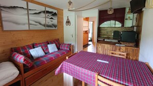 Una habitación acogedora con un sofá de madera, una mesa de comedor y una zona de cocina.