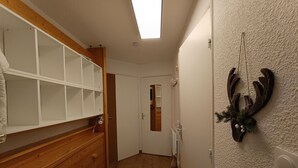 Un pasillo con un banco de madera, una puerta blanca y una decoración de cuernos de ciervo en la pared.
