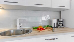 Una cocina moderna con un lavamanos de acero inoxidable, una tabla de madera con verduras y una cafetera.