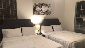 Une chambre d’hôtel avec deux lits, une table de chevet avec une lampe et une œuvre d’art murale.