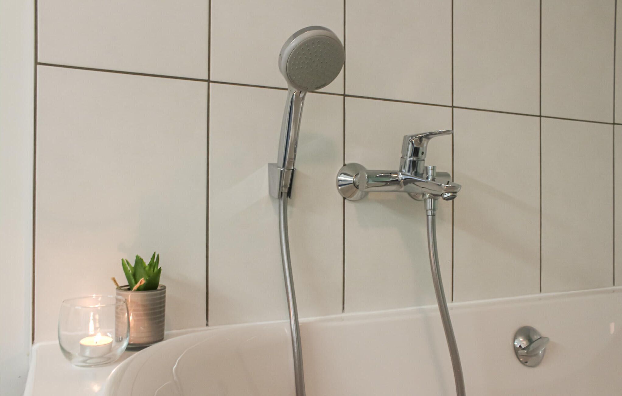 Un baño con bañera, ducha de mano y grifo empotrado.