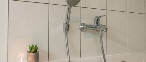 Un baño con bañera, ducha de mano y grifo empotrado.