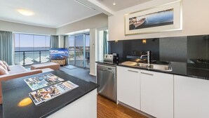 A modern kitchen with a black countertop, white cabinets, and a stainless steel dishwasher. - Stunning 270 degrees view of the Ocean, Beach & Marina Views (mandurah)