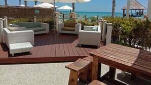 A deck with outdoor seating, including sofas and a table, overlooking a beach. - Stunning 270 degrees view of the Ocean, Beach & Marina Views (mandurah)