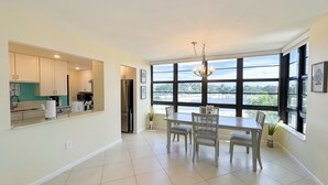 A modern kitchen with a dining area, large windows, and a view of the outdoors. - South Seas T4- 306: Beautiful end unit condo, Beach Front (Marco Island)