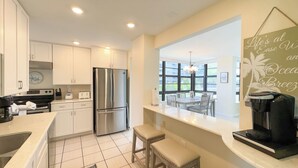 A modern kitchen with white cabinets, a stainless steel refrigerator, and a coffee machine. - South Seas T4- 306: Beautiful end unit condo, Beach Front (Marco Island)