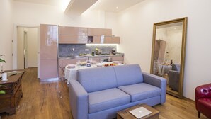 Una sala de estar moderna con un sofá gris, una mesa de centro de madera y una zona de comedor con una mesa dispuesta para dos personas.