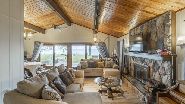 Un salón amplio con chimenea, techo de madera y ventanas grandes.