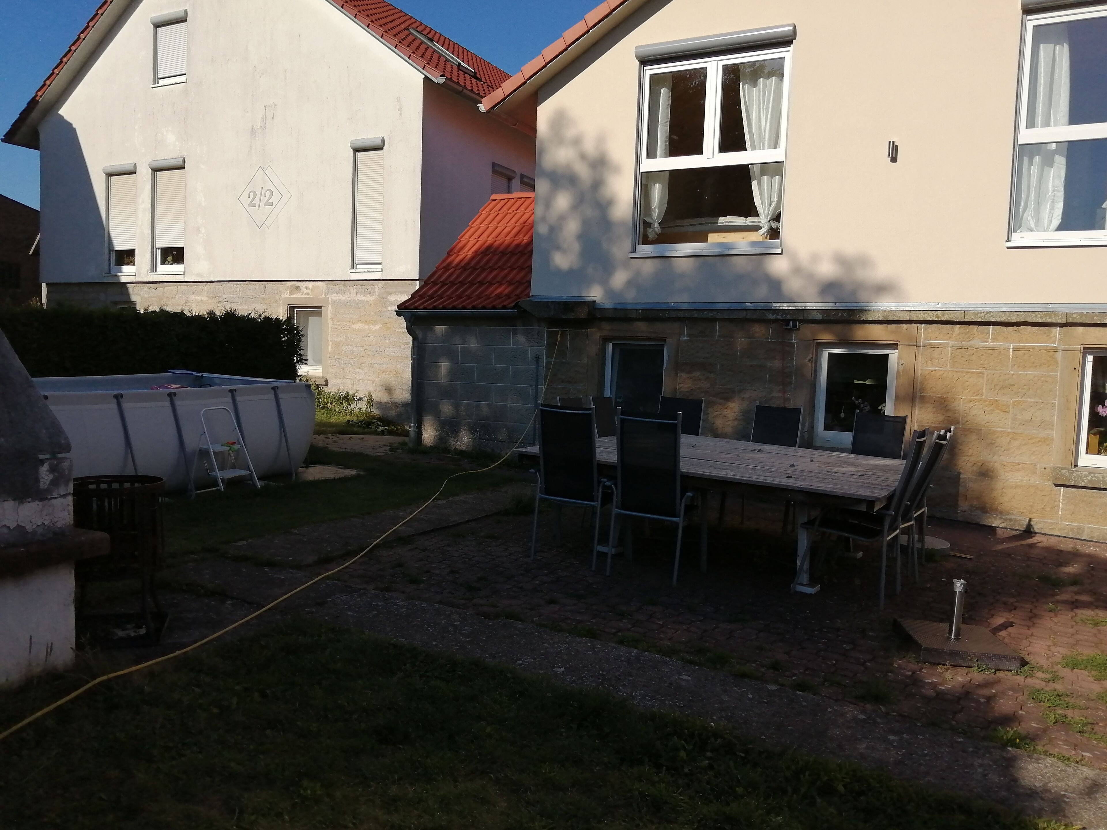 A residential building with a stone exterior, a tiled roof, and a patio area with a table and chairs.