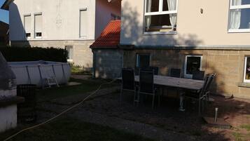 A residential building with a stone exterior, a tiled roof, and a patio area with a table and chairs.
