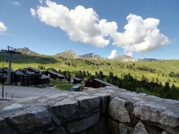 A mountain resort with stone walls, a parking area, and buildings with a view of the surrounding mountains.