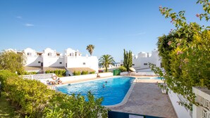 A swimming pool surrounded by lush greenery and white buildings. - Top renovated townhouse with pool and sea access (Porches)