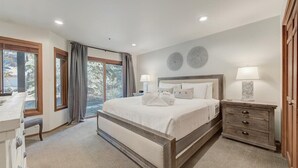 Un dormitorio con una cama grande, una mesita de noche, un escritorio y una ventana con cortinas.