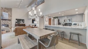 Una cocina moderna con una isla grande, electrodomésticos integrados y un muro decorativo de piedra.