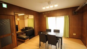 A modern room with a wooden floor, a dining table with chairs, a sofa, and a television.