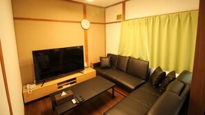 A modern living room with a flat-screen TV, a sofa, a coffee table, and a clock on the wall.