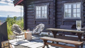 A rustic wooden cabin with a patio area featuring two chairs, a table, and a hanging chair. - 3 bedroom amazing home in Uvdal (Uvdal)