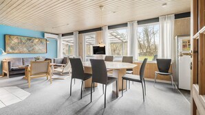 Et moderne spiseområde med et stort bord, stole, en sofa og et fjernsyn.