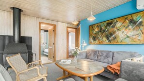 En hyggelig stue med pejs, sofa, sofabord og et stort abstrakt maleri på væggen.
