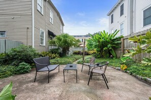 Enjoy a serene outdoor space surrounded by lush plants and a wooden fence, perfect for relaxing with a meal at the metal table and chairs.