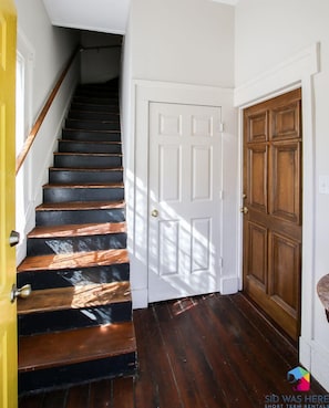 Stairs lead to an upper floor, flanked by a door on the right and a door on the left.