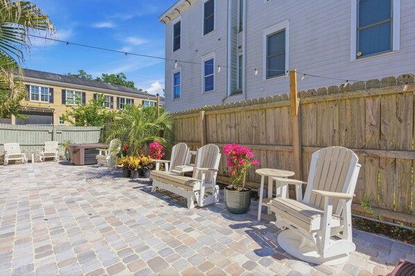 A patio area with outdoor furniture, a wooden fence, and a building in the background.
