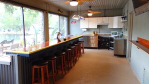 Une cuisine avec un coin bar, des tabourets de bar et une vue sur l’extérieur.