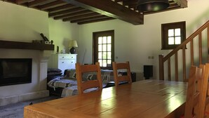 A dining area with a wooden table and chairs, a fireplace, and a staircase. - Charming traditional Norman House near Honfleur & Deauville  (Cormeilles)