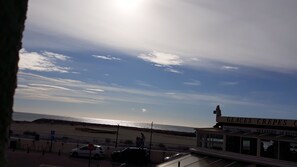 A coastal view with a restaurant named "GLACES CREPES" and a beach in the background. - A very pleasant duplex with a loggia and a view of the sea (Saintes-Maries-de-la-Mer)